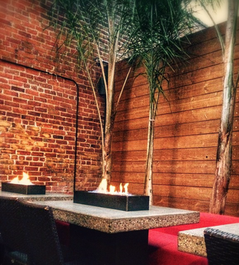 Outdoor Patio with brick walls, palm trees, and cozy fire pit tables